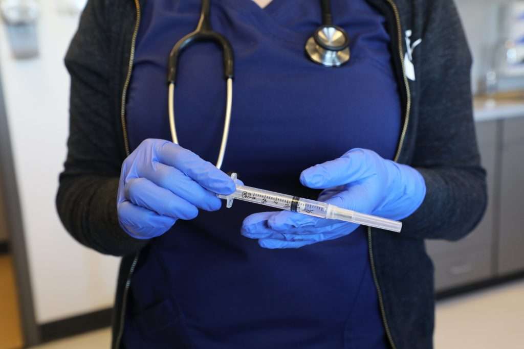 Closeup photo of a healthcare provider holding a syringe