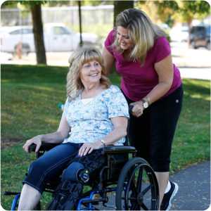 Daughter pushes mother in wheelchair down sidewalk